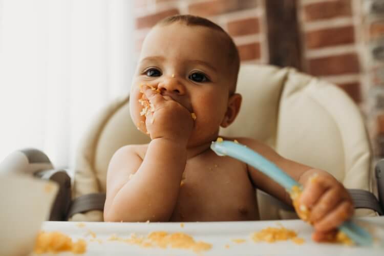 有趣的婴儿在厨房里吃健康的食物